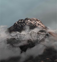 a mountain covered in clouds under a cloudy sky