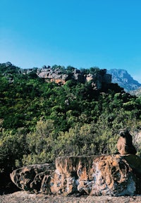 a person is sitting on a rock in the middle of a mountain