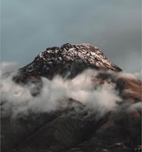 a mountain covered in clouds under a cloudy sky