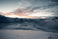 the sun is setting over a snow covered mountain